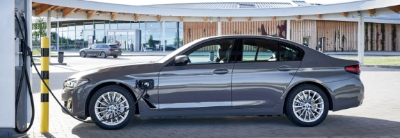 Grauer BMW in moderner Garage mit Glasfront, Stadt und Wasser im Hintergrund
