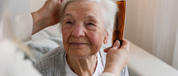 Eine Person kämmt die Haare einer älteren Person