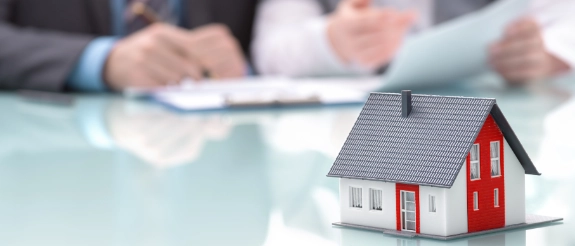 Maklervertrag: Geschäftsleute unterzeichnen Dokument neben Miniaturhaus auf Schreibtisch