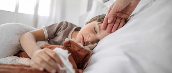 Ein Kind ist im Urlaub krank geworden. Es liegt im Bett und schläft. 