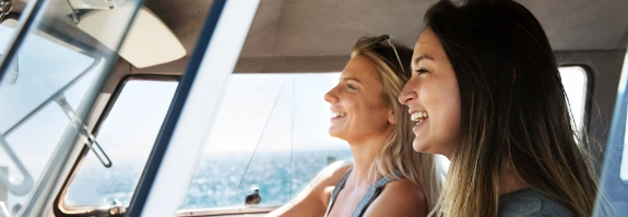 Zwei Frauen fahren mit dem Auto an der Küste entlang.