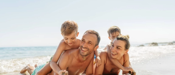 Eine fröhliche Familie mit zwei Kindern auf Reisen am Strand. 