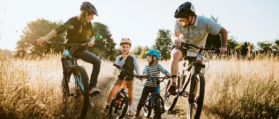 Eine Familie fährt mit ihren Fahrrädern einen Feldweg entlang.