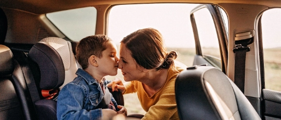 Mutter schnallt Kind im Kindersitz an.