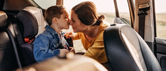 Mutter schnallt ihren Sohn im Kindersitz an.