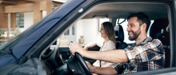 Mann und Frau fahren in einem blauen Auto.