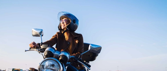 Eine Frau sitzt lächelnd auf ihrem Motorrad, das sie durch den B196-Führerschein fahren darf.