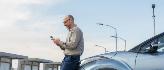 Man sieht einen Mann mit seinem Auto der sich zu Überführungskennzeichen informiert.