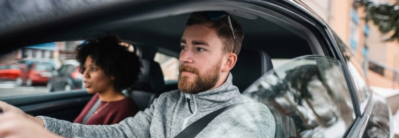 Mann und Frau fahren mit dem Auto durch die Stadt.