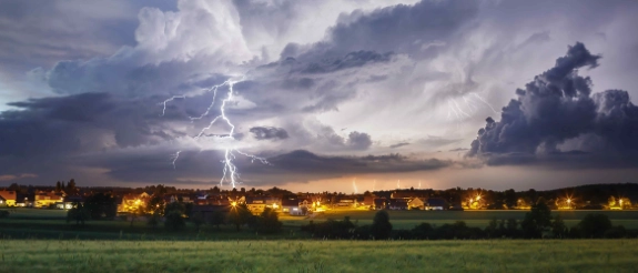 Ein Gewitter mit Blitzen über einer Ortschaft.