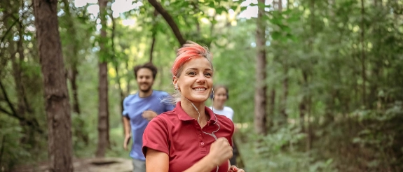 Mehrere Personen joggen durch einen Wald.