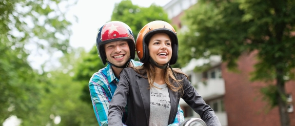 Eine Frau und ein Mann auf einem Moped haben sich über die Unterschiede von Rollern und anderen Kleinkrafträdern informiert.