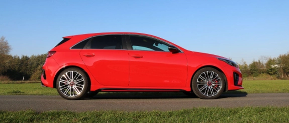 Roter Audi A3 Sportback auf grüner Wiese, Seitenansicht, klarer blauer Himmel, parkend in ländlicher Umgebung