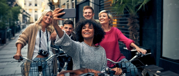 Fünf Freunde mit Fahrrädern lachen zusammen in einer Fußgängerzone einer Stadt