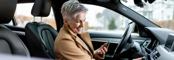 Frau bedient das Infotainment-System im Auto.
