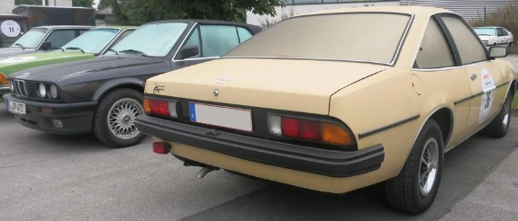Beige Mercedes-Benz Limousine aus den 1980ern, Heckansicht mit Rückleuchten, auf Parkplatz geparkt