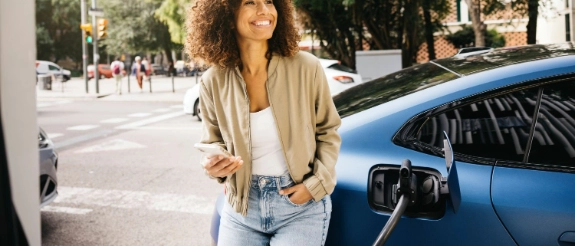 Eine Frau lädt per App ihr E-Auto unterwegs an einer Ladesäule.