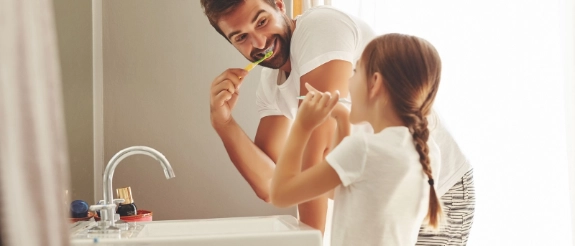 Vater und Tochter waschen sich die Hände am Waschbecken im Badezimmer