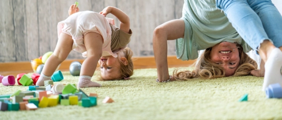 Mutter und Baby spielen zusammen auf dem Boden mit bunten Spielzeugen und Bausteinen