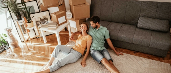Ein junges Paar ist umgezogen und sitzt in der neuen Wohnung.