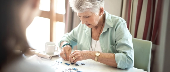 Eine ältere Person setzt ein Puzzle an einem Tisch zusammen