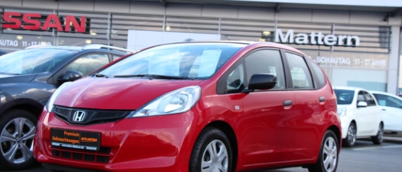 Roter Honda Jazz Kleinwagen auf Autohändler-Gelände mit weiteren Fahrzeugen im Hintergrund