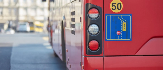 Rückseite eines roten Busses mit Geschwindigkeitsbegrenzung 50, Ampel und Stadtstraße im Hintergrund