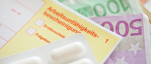 Gelber Infoblatt zur Krankenversicherung mit weißer Tablettenpackung und Eurogeldscheine im Hintergrund