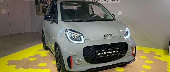 Weißer Kia e-Soul Elektroauto in Ausstellungsraum auf gelbem Boden präsentiert