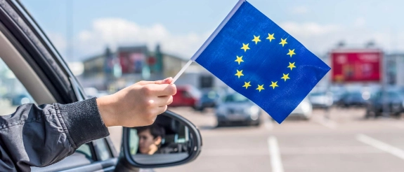 Person hält kleine EU-Fahne aus dem Autofenster.