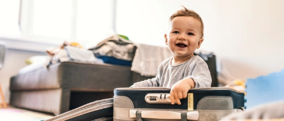 Lachender Kleinkind sitzt zwischen Werkzeugen und Bauelementen im hellen Wohnzimmer