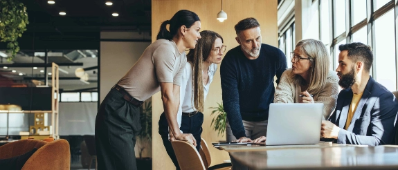 5 Verwandte sitzen und stehen im Büro unterhalten sich über ihre Arbeit im Familienbetrieb.
