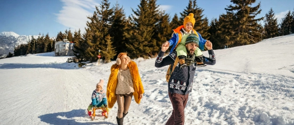Eine Familie genießt ihren Skiurlaub und wandert mit einem Schlitten durch den Schnee.
