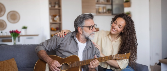 Ein Mann spielt einer Frau mit der Gitarre vor als Symbol für die Lebensfreude, die man durch die Altersrente haben könnte.