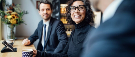 Geschäftsleute in Büro trinken Kaffee und unterhalten sich während eines Meetings am Tisch