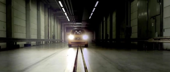 Zug fährt durch industrielle Tunnelanlage mit Betonwänden und Deckenleuchten