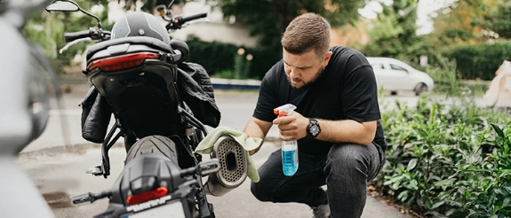 Motorrad waschen: Ein Biker reinigt ein Motorrad mit einem Tuch.