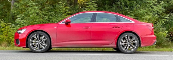 Roter Audi A6 Sedan parkt am Straßenrand vor grünem Waldgebiet mit Bäumen