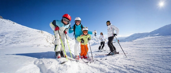 Eine Familie fährt gemeinsam Ski und ist mit passenden Versicherungen für den Skiurlaub abgesichert. 
