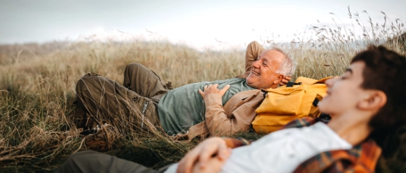 Großvater und Enkel leigen entspannt in einem Feld.