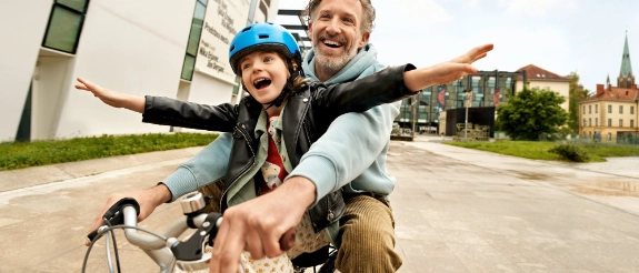 Vater und Sohn haben ohne Angst Spaß beim Fahrradfahren, dank der privaten Unfallversicherung für Kinder.