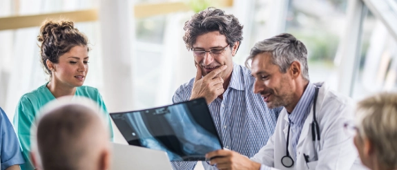 Ärzte und Patienten besprechen Röntgenaufnahmen beim Termin in der Praxis