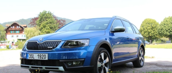 Blauer SUV steht auf grüner Wiese vor Haus und Bäumen, sonniger Sommertag
