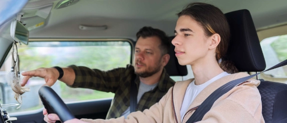 Zwei Personen sitzen im Auto, Mann am Steuer und Frau auf Beifahrersitz während einer Fahrt.