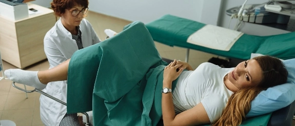 Therapeutin massiert Bein einer älteren Patientin auf Behandlungsliege in Praxisraum