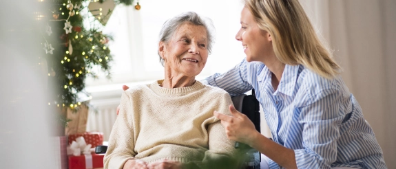Eine Angehörige feiert Weihnachten gemeinsam mit einer pflegebedürftigen Seniorin.