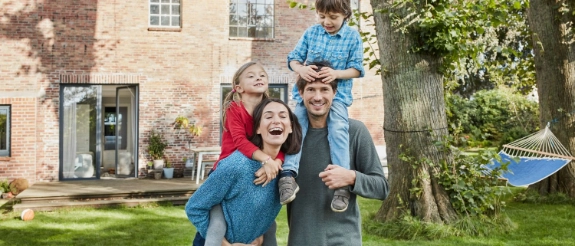 Lachende Familie zu Hause als Symbol für die Vorsorge-Kooperation zwischen R+V und familie.de.