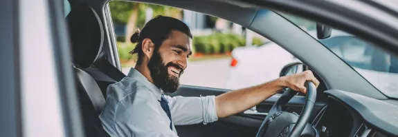Mann sitzt im geparktem Auto.