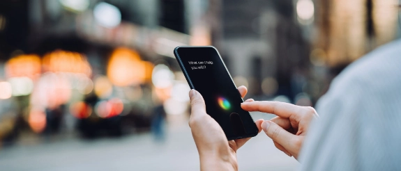 Person hält Smartphone in der Hand und benutzt Sprachassistenten.