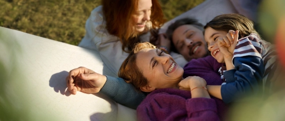 Eine Familie mit zwei Kindern liegt vergnügt in einer Hängematte.